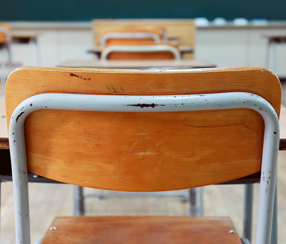 Primo piano di una sedia, presa da dietro, in unaula scolastica